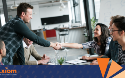 Business professionals shaking hands in a collaborative meeting, symbolizing trust and teamwork, with Axiom Human Resource Solutions branding in the corner, reflecting a people-centric culture.