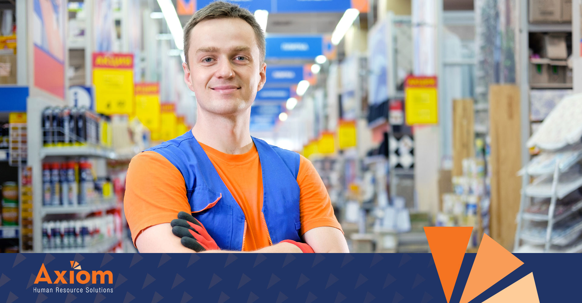 Young male worker in a blue vest and orange shirt smiling in a retail environment, representing youth employment compliance in Indiana by Axiom Human Resource Solutions.