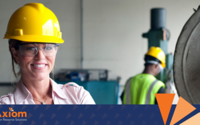 Manufacturing HCM Solutions 6 Human Capital Management Solutions for Manufacturing Woman in safety gear smiling in a manufacturing environment, with a colleague in the background, representing Axiom Human Resource Solutions' focus on workforce management in manufacturing.
