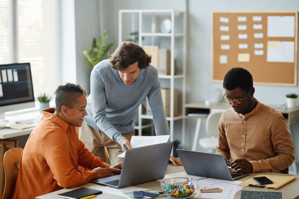 Team of HR professionals collaborating over a laptop checking for payroll errors.