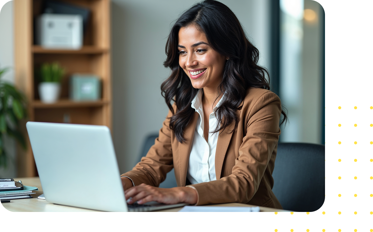 Woman in professional attire smiling while working on a laptop, representing HR leaders engaging with data-driven insights and workforce strategies.