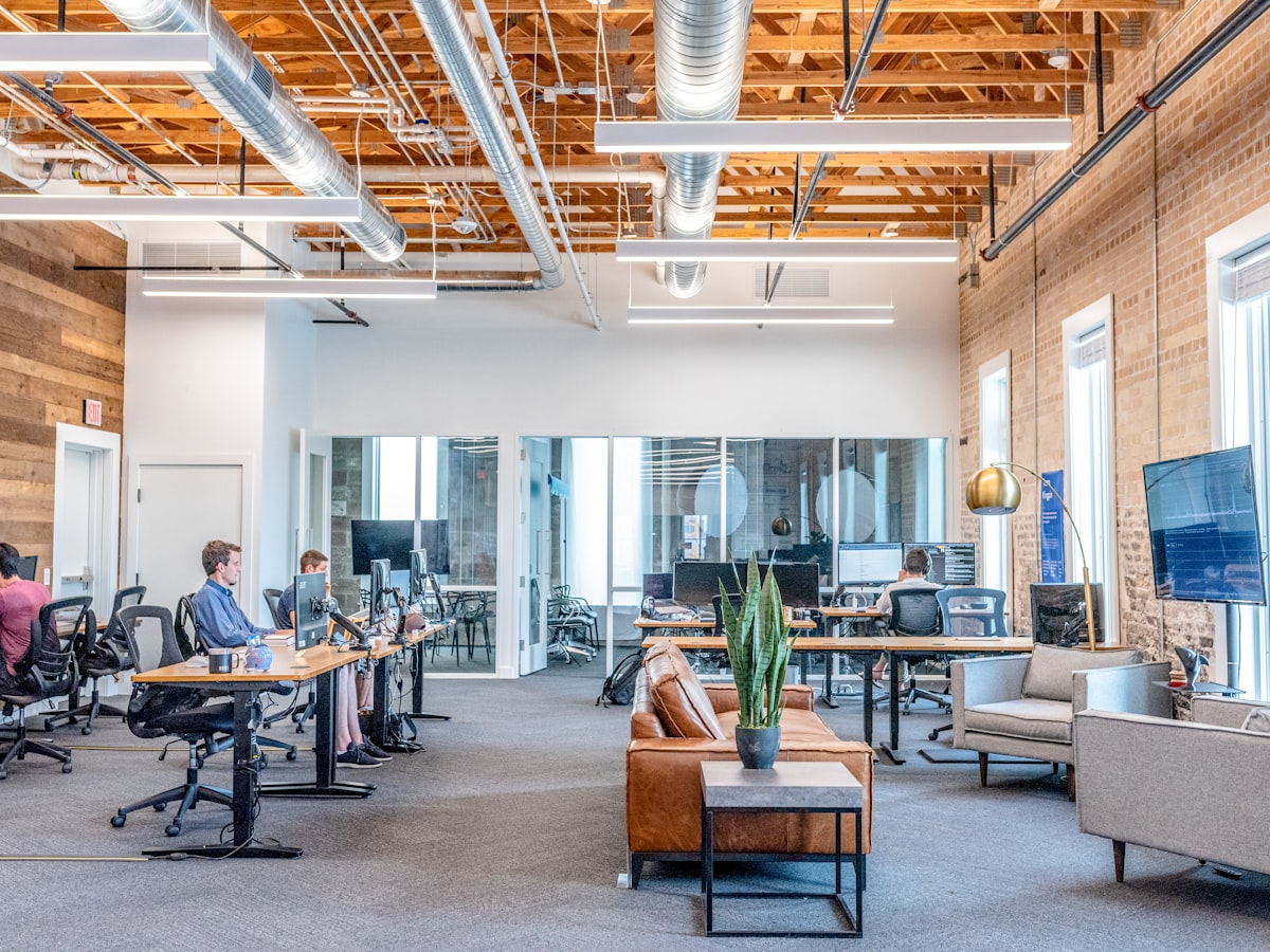Modern office space with employees working at desks, featuring a mix of collaborative and individual workstations, emphasizing a professional environment suitable for mid-market HR teams.