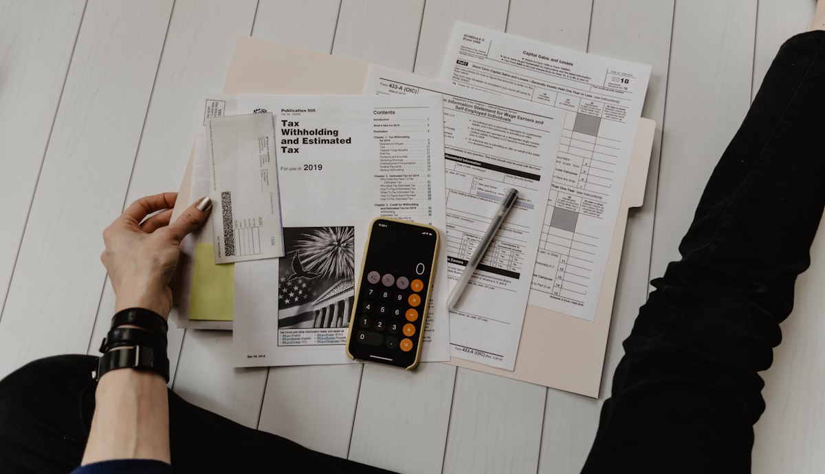 UKG Ready vs Paycor: 6 Reasons Mid-Market Wins with UKG 5 UKG Ready vs Paycor Person reviewing tax documents and calculator on a table, illustrating financial preparation and analysis in the context of HCM software selection.