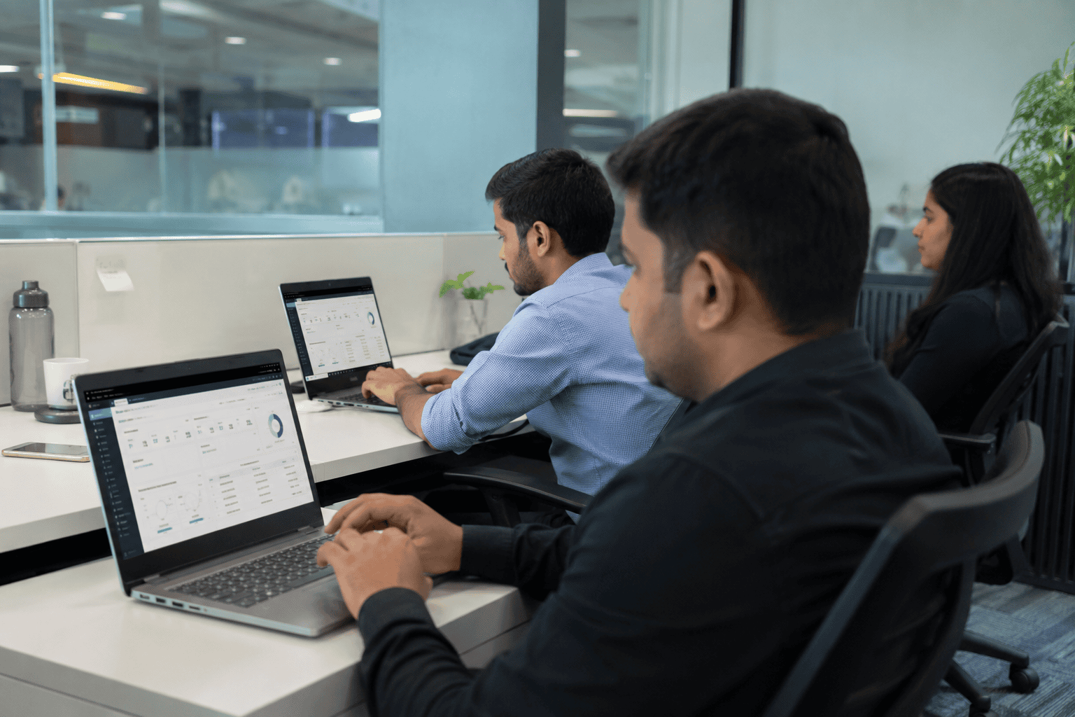 Team of HR professionals collaborating over a laptop checking for payroll errors.